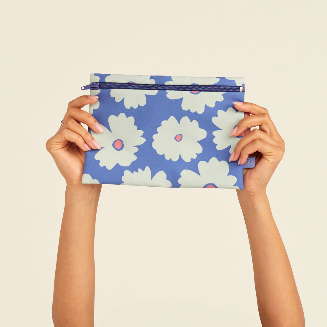 Modell hält die ooia Wetbag Edition 24/25, mit Daisy Aufdruck und flüssigkeitsundurchlässigem Innenstoff