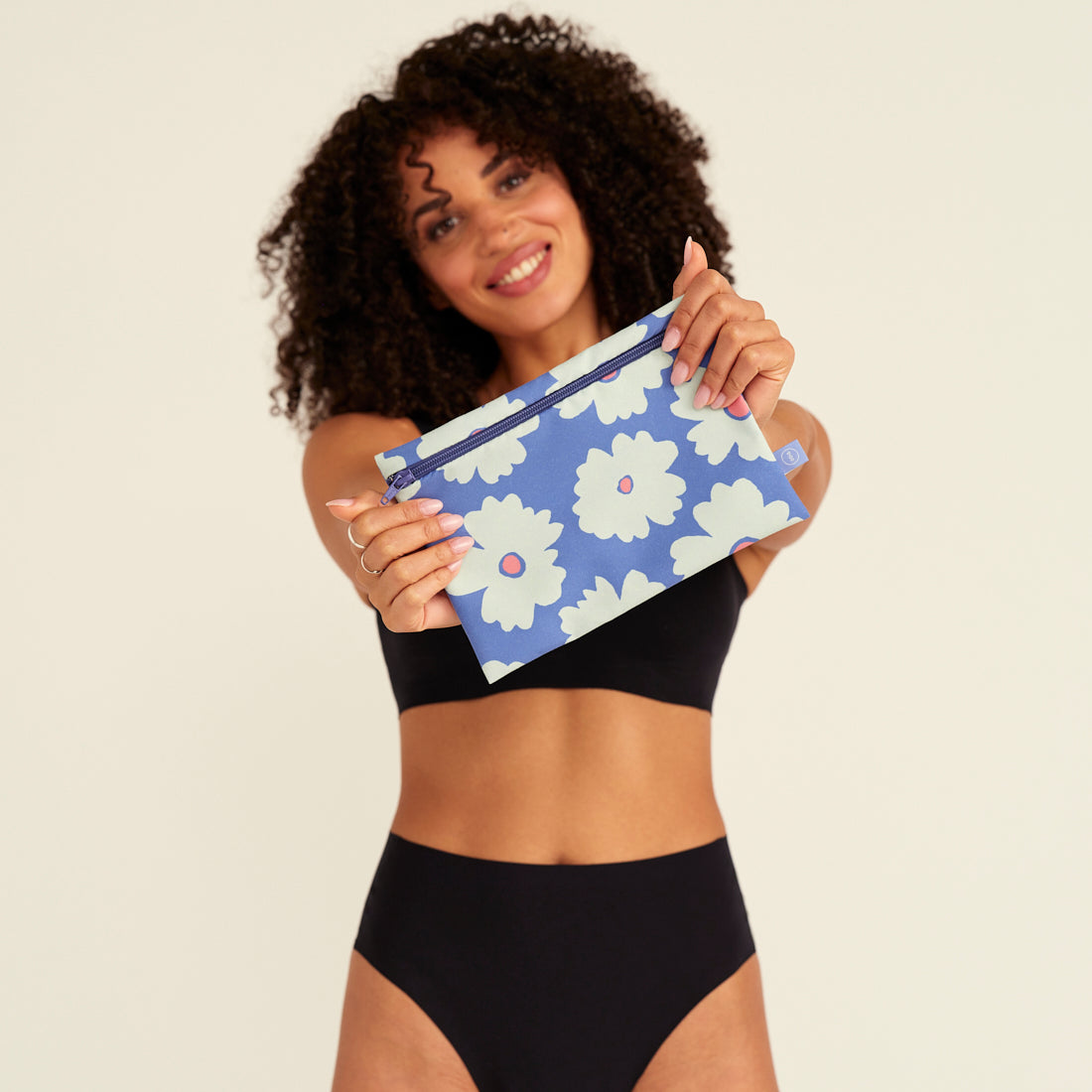 Modell hält die ooia Wetbag Edition 24/25, mit Daisy Aufdruck und flüssigkeitsundurchlässigem Innenstoff