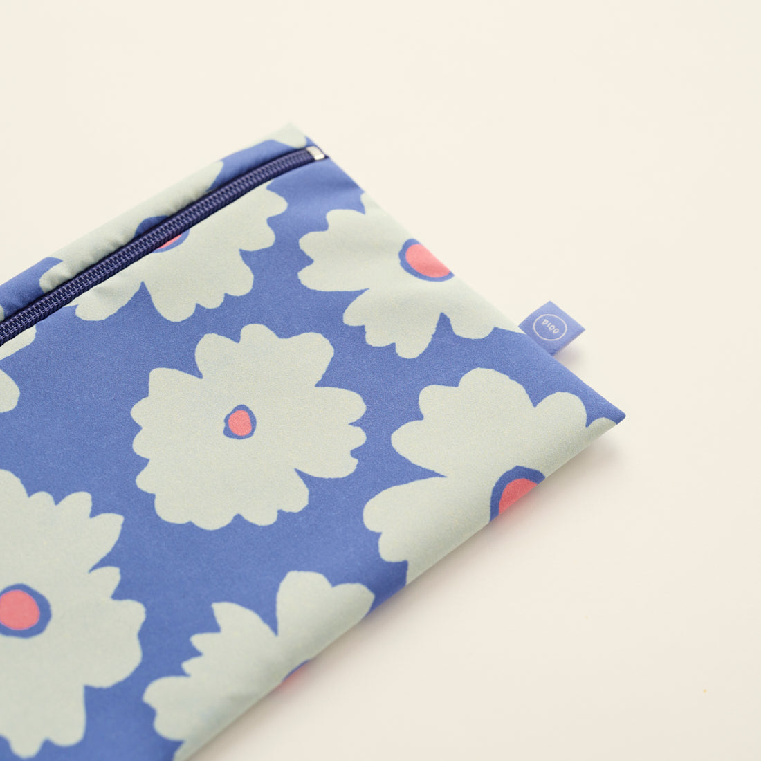 Modell hält die ooia Wetbag Edition 24/25, mit Daisy Aufdruck und flüssigkeitsundurchlässigem Innenstoff, Detailansicht