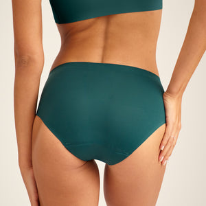 Modell trägt ooia Hipster Seamless in Grün – nahtlose Periodenunterwäsche. Rückansicht.