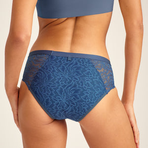 Modell trägt ooia Hipster Allover Lace Extra Strong in Smoky Blue – Periodenunterwäsche mit durchgehender Spitze und starker Saugstärke. Rückansicht.