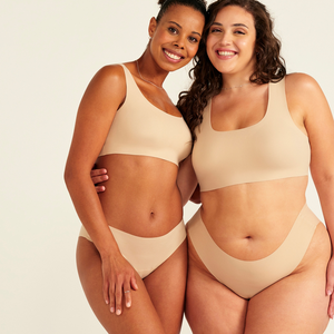 Zwei Models unterschiedlicher Konfektion tragen ooia All-You-Need Bra Top in Beige – bügelloses, nahtloses Bustier mit breiten Trägern, dazu passed Periodenslip Seamless in Beige.