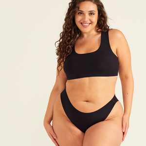 Modell trägt ooia All-You-Need Bra Top in Größe XL in Schwarz – bügelloses, nahtloses Bustier mit breiten Trägern, dazu ooia Periodenslip Seamless schwarz.