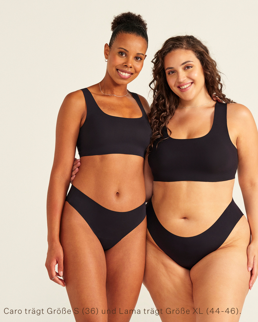 Zwei Models unterschiedlicher Konfektion tragen ooia All-You-Need Bra Top in Schwarz – bügelloses, nahtloses Bustier mit breiten Trägern, dazu ooia Periodenslip Seamless schwarz.