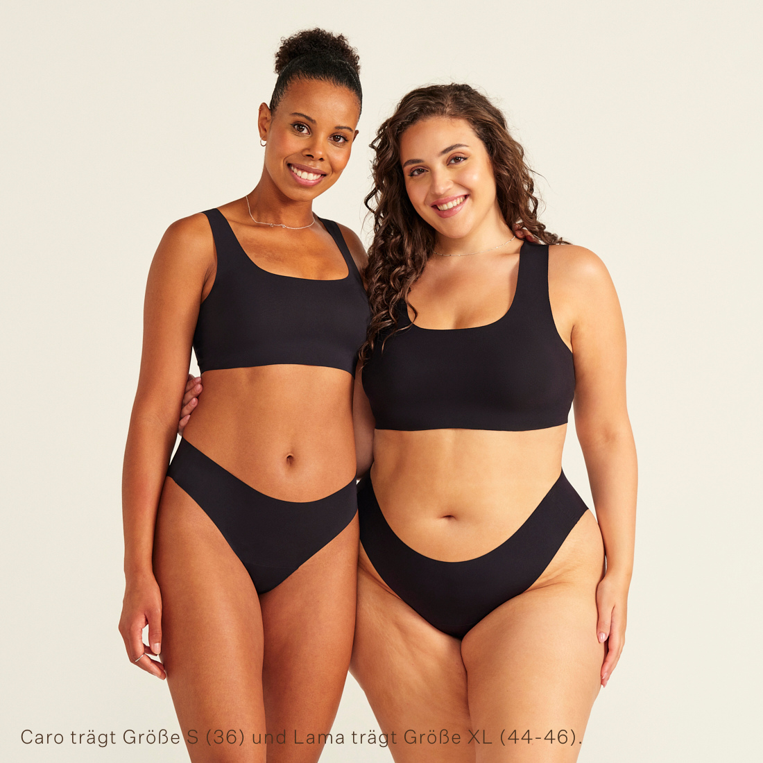Zwei Models unterschiedlicher Konfektion tragen ooia All-You-Need Bra Top in Schwarz – bügelloses, nahtloses Bustier mit breiten Trägern, dazu ooia Periodenslip Seamless schwarz.