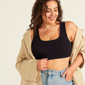Modell trägt ooia All-You-Need Bra Top in Schwarz – bügelloses, nahtloses Bustier mit breiten Trägern, dazu Jacke und Jeans.