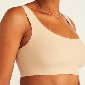 Modell trägt ooia All-You-Need Bra Top in Beige – bügelloses, nahtloses Bustier mit breiten Trägern