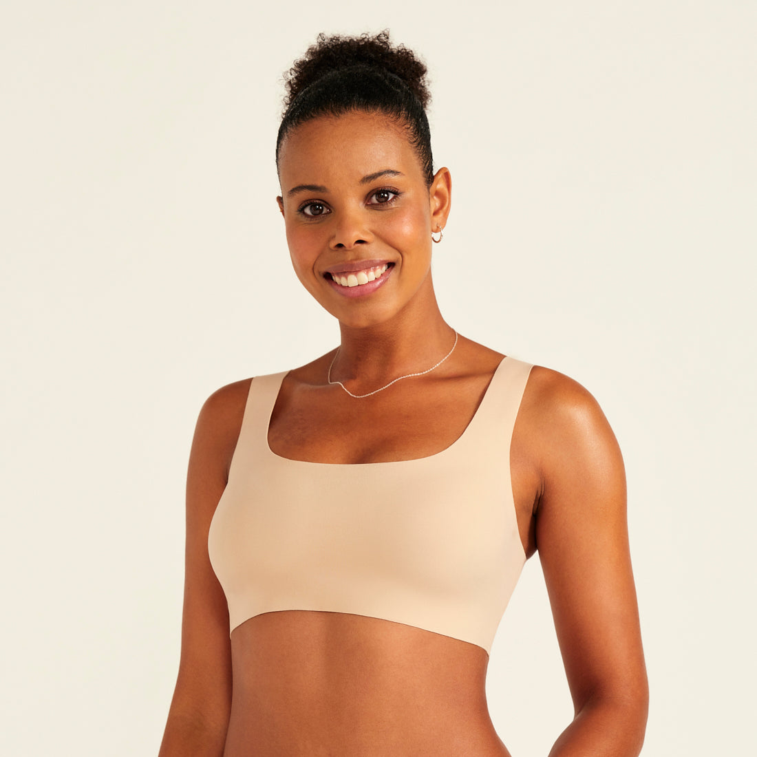 Modell trägt ooia All-You-Need Bra Top in Beige – bügelloses, nahtloses Bustier mit breiten Trägern