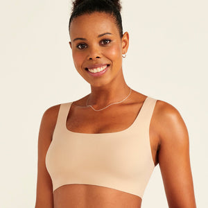 Modell trägt ooia All-You-Need Bra Top in Beige – bügelloses, nahtloses Bustier mit breiten Trägern