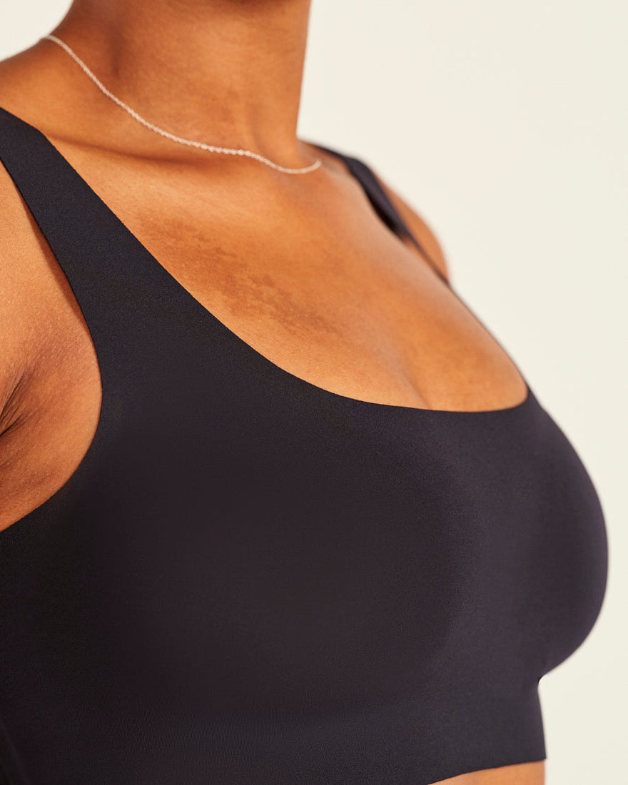 Modell trägt ooia All-You-Need Bra Top in Schwarz – bügelloses, nahtloses Bustier mit breiten Trägern.
