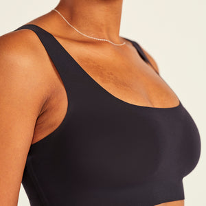 Modell trägt ooia All-You-Need Bra Top in Schwarz – bügelloses, nahtloses Bustier mit breiten Trägern.