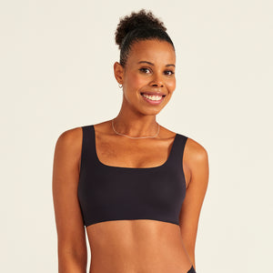 Modell trägt ooia All-You-Need Bra Top in Schwarz – bügelloses, nahtloses Bustier mit breiten Trägern.