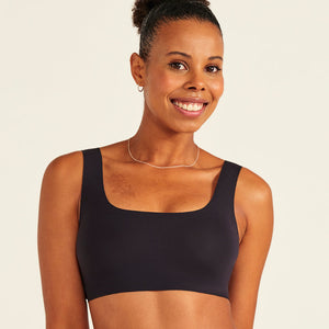 Modell trägt ooia All-You-Need Bra Top in Schwarz – bügelloses, nahtloses Bustier mit breiten Trägern.