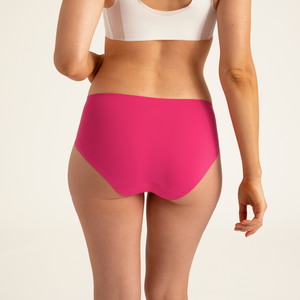 Modell trägt ooia Hipster Seamless in Hot Pink - nahtlose Periodenunterwäsche. Rückansicht.