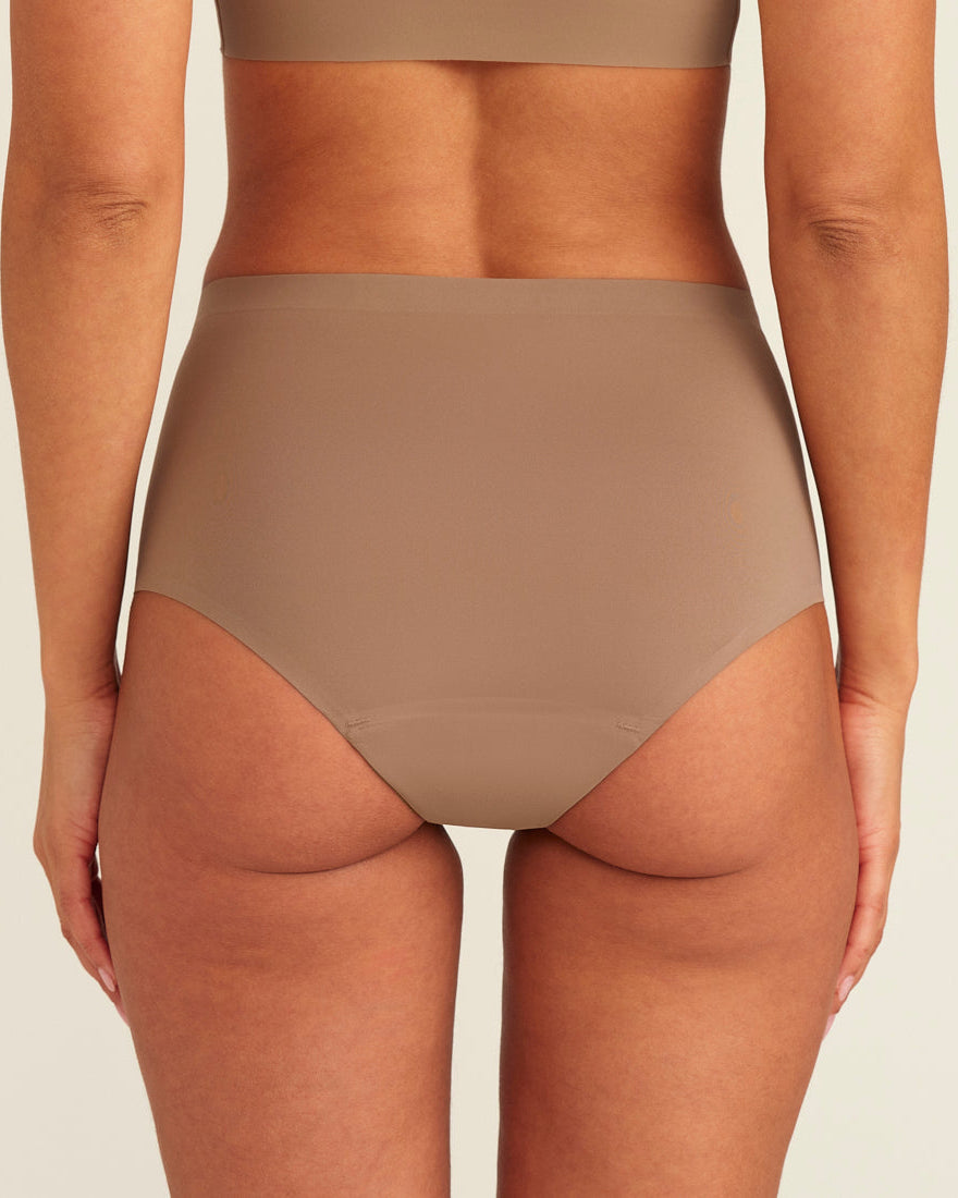 Modell trägt ooia Periodenunterwäsche Highwaist Seamless in Taupe mit hohem Bund und nahtlosem Design, Rückansicht