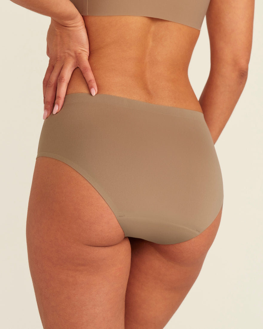 Modell trägt ooia Periodenunterwäsche Hipster Seamless in Taupe mit nahtlosem Design, Rückansicht
