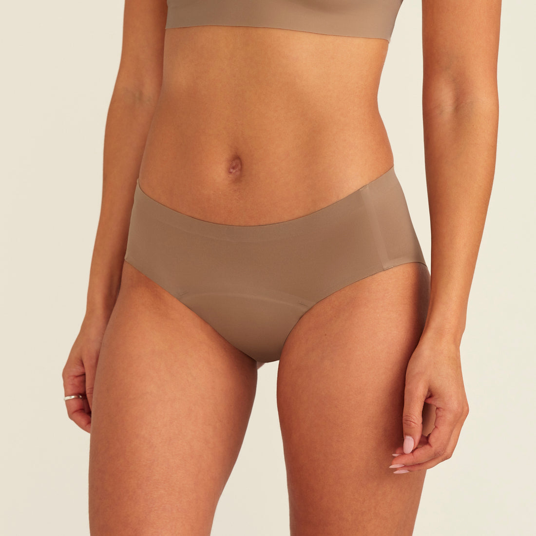 Modell trägt ooia Periodenunterwäsche Hipster Seamless in Taupe mit nahtlosem Design
