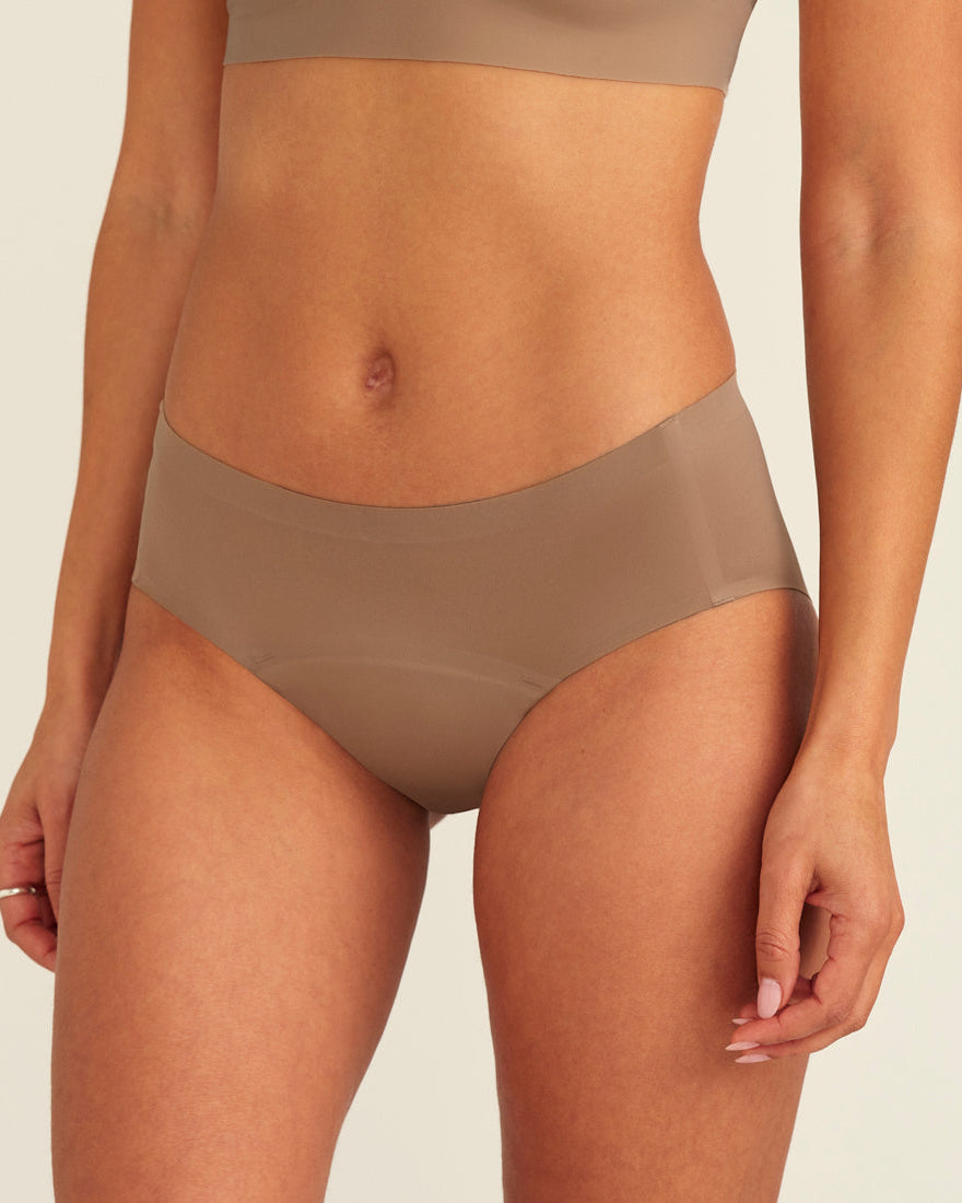 Modell trägt ooia Periodenunterwäsche Hipster Seamless in Taupe mit nahtlosem Design