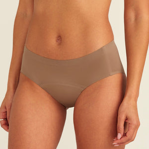 Modell trägt ooia Periodenunterwäsche Hipster Seamless in Taupe mit nahtlosem Design