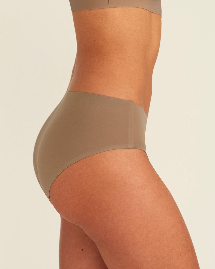 Modell trägt ooia Periodenunterwäsche Hipster Seamless in Taupe mit nahtlosem Design