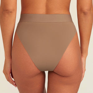 Modell trägt ooia Periodenslip Seamless Cheeky in Taupe mit hohem Beinausschnitt, Rückansicht