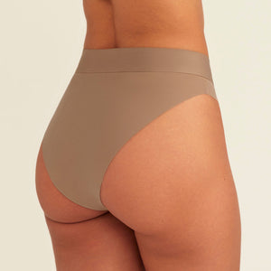 Modell trägt ooia Periodenslip Seamless Cheeky in Taupe mit hohem Beinausschnitt, Rückansicht