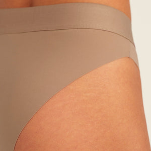 Modell trägt ooia Periodenslip Seamless Cheeky in Taupe mit hohem Beinausschnitt, Detailansicht nahtloses Design
