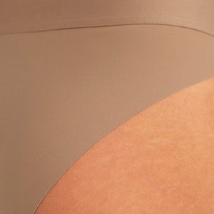 Modell trägt ooia Periodenslip Seamless Cheeky in Taupe mit hohem Beinausschnitt, Detailansicht nahtloses Design