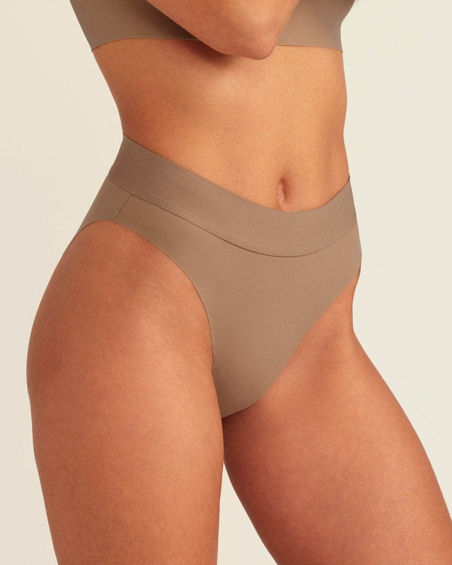 Modell trägt ooia Periodenslip Seamless Cheeky in Taupe mit hohem Beinausschnitt