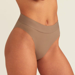 Modell trägt ooia Periodenslip Seamless Cheeky in Taupe mit hohem Beinausschnitt