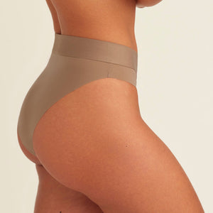 Modell trägt ooia Periodenslip Seamless Cheeky in Taupe mit hohem Beinausschnitt