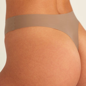Modell trägt ooia Periodenunterwäsche String Seamless in Taupe mit leichter Saugstärke, Detailansicht nahtloses Design