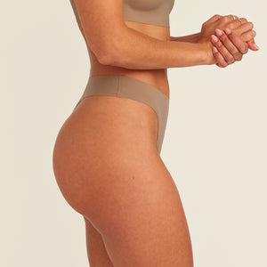 Modell trägt ooia Periodenunterwäsche String Seamless in Taupe mit leichter Saugstärke