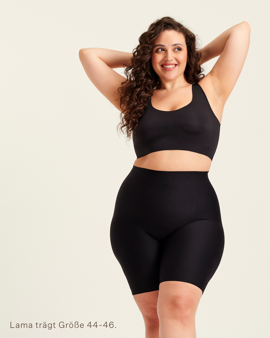 kurviges Modell trägt ooia Shape Short Thigh Saving in Schwarz – figurformende Short mit Oberschenkelschutz.