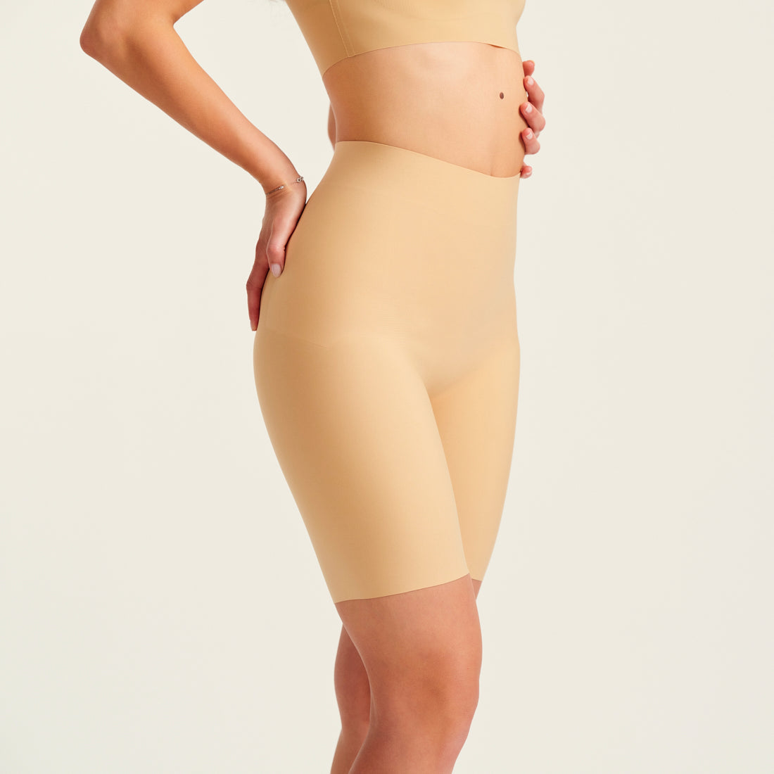 Modell trägt ooia Shape Short Thigh Saving in Beige – figurformende Short mit Oberschenkelschutz