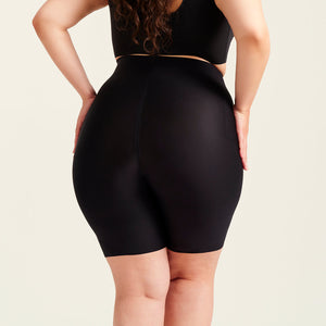 kurviges Modell trägt ooia Shape Short Thigh Saving in Schwarz – figurformende Short mit Oberschenkelschutz