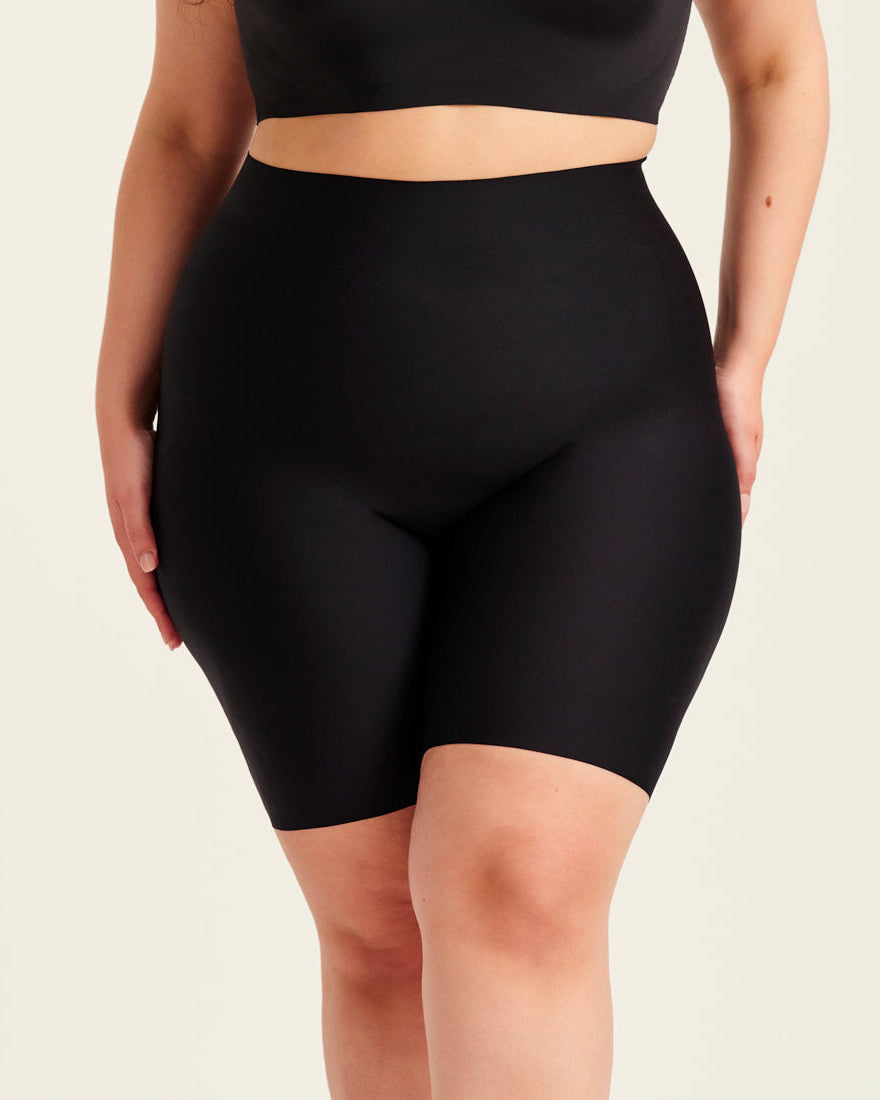 kurviges Modell trägt ooia Shape Short Thigh Saving in Schwarz – figurformende Short mit Oberschenkelschutz