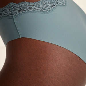 Modell trägt Periodenunterwäsche Slip Seamless Lace extra stark in blau mit nahtlosem Design mit Spitze am Bund.
Seitenansicht, Detail