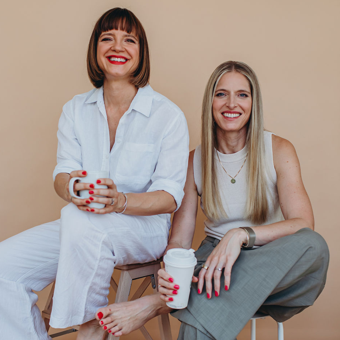 Kristine Zeller und Kati Ernst posieren gemeinsam mit Kaffeebechern in der Hand