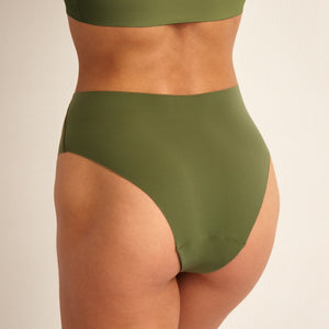 Modell trägt ooia Highwaist Seamless Cheeky in Khaki – nahtlose Periodenunterwäsche mit hoch geschnittenen Beinausschnitt. Rückansicht.