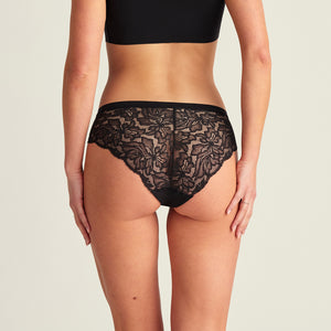 Modell trägt ooia Everyday Hipster Seamless Lace in Schwarz, nahlos vorn und Spitze am Gesäß – ersetzt Slipeinlagen, Rückansicht