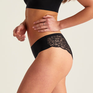 Modell trägt ooia Everyday Hipster Seamless Lace in Schwarz, nahlos vorn und Spitze am Gesäß – ersetzt Slipeinlagen