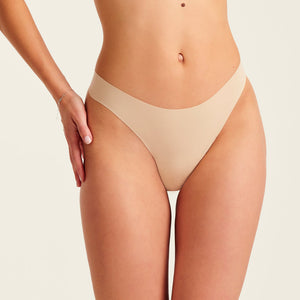 Modell trägt ooia Periodenunterwäsche String Seamless in Beige - nahtloser String mit leichter Saugstärke