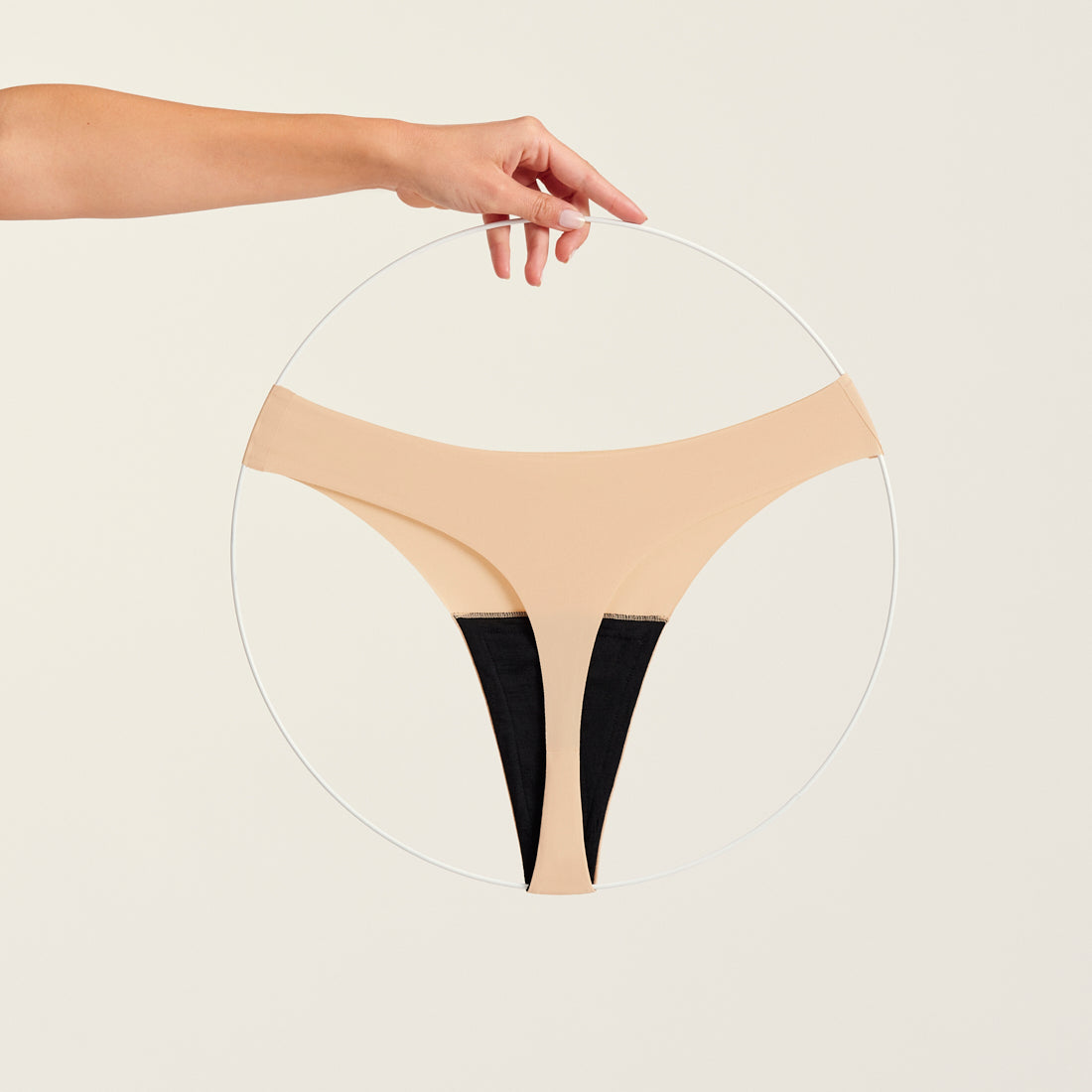 Modell trägt ooia Periodenunterwäsche String Seamless in Beige - nahtloser String mit leichter Saugstärke. Freisteller.