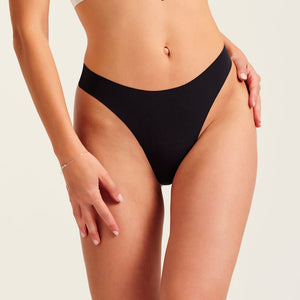 Modell trägt ooia Periodenunterwäsche String Seamless in Schwarz - nahtloser String mit leichter Saugstärke.