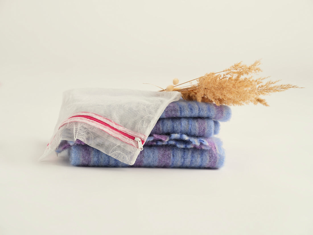 Ooia Washbag aus feinmaschigem Netzmaterial – ideal zum Waschen von Periodenunterwäsche in der Maschine. ooia Washbag liegt auf Handtüchern.