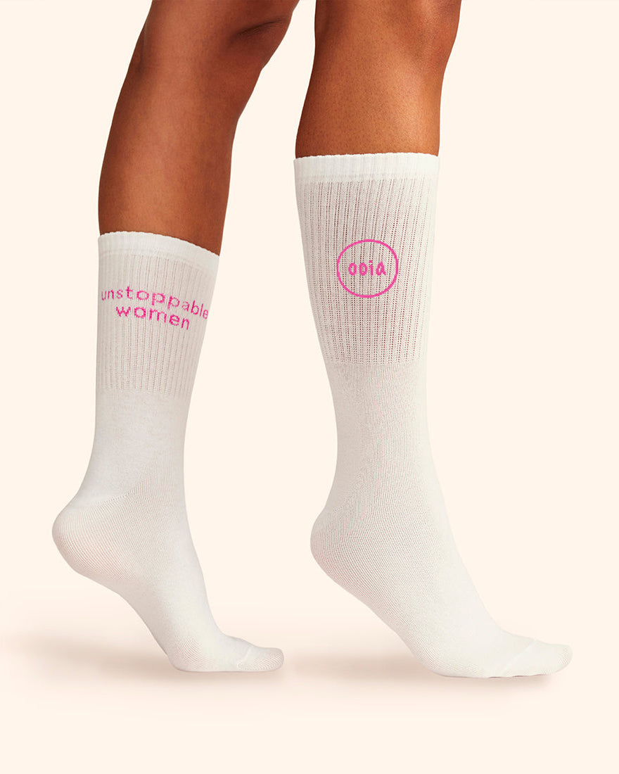 Modell trägt weiße wadenhohe ooia Socken mit dem pinken Aufdruck: Unstoppable Woman