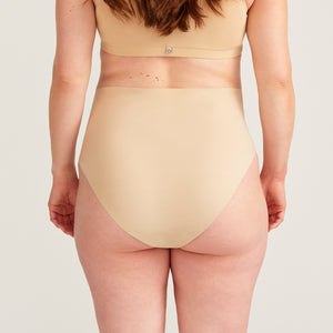 Modell trägt beigen moms Still BH und ooia The Belly Hugger Schwangerschafts-Panty in Beige mit hohem Bund, Rückansicht