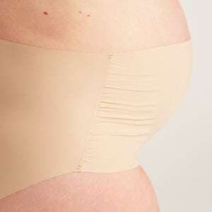 Modell trägt beigen moms Still BH und ooia The Belly Hugger Schwangerschafts-Panty in Beige mit hohem Bund, Detailansicht elastischer Bund