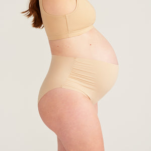Modell trägt beigen moms Still BH und ooia The Belly Hugger Schwangerschafts-Panty in Beige mit hohem Bund, Seitenansicht